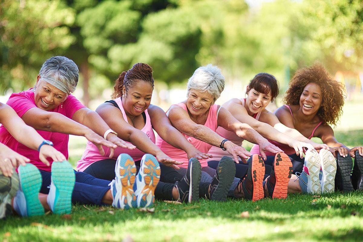 The National Institutes of Health — Group of women doing yoga stretches in a park.