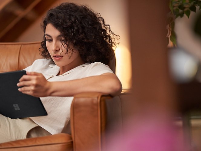 Microsoft — A person sitting on a couch looking at a tablet