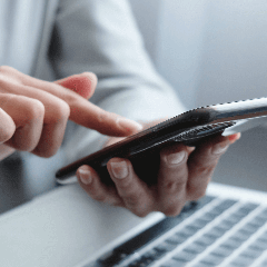 HugeDomains — Image of a person using a phone for mobile banking or online transactions.